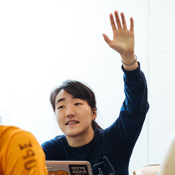 A German 研究 major student raises her hand in class.